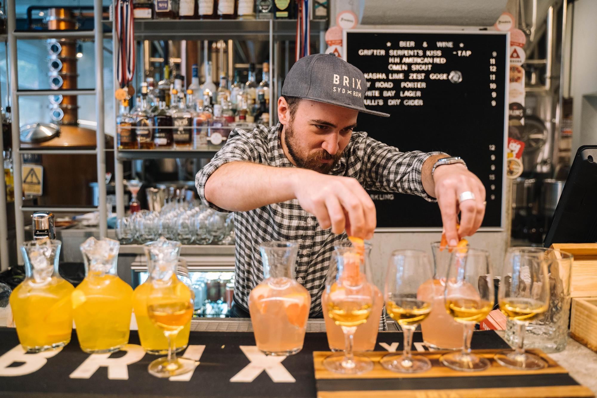A bartender is adding garnishes to a row of cocktails